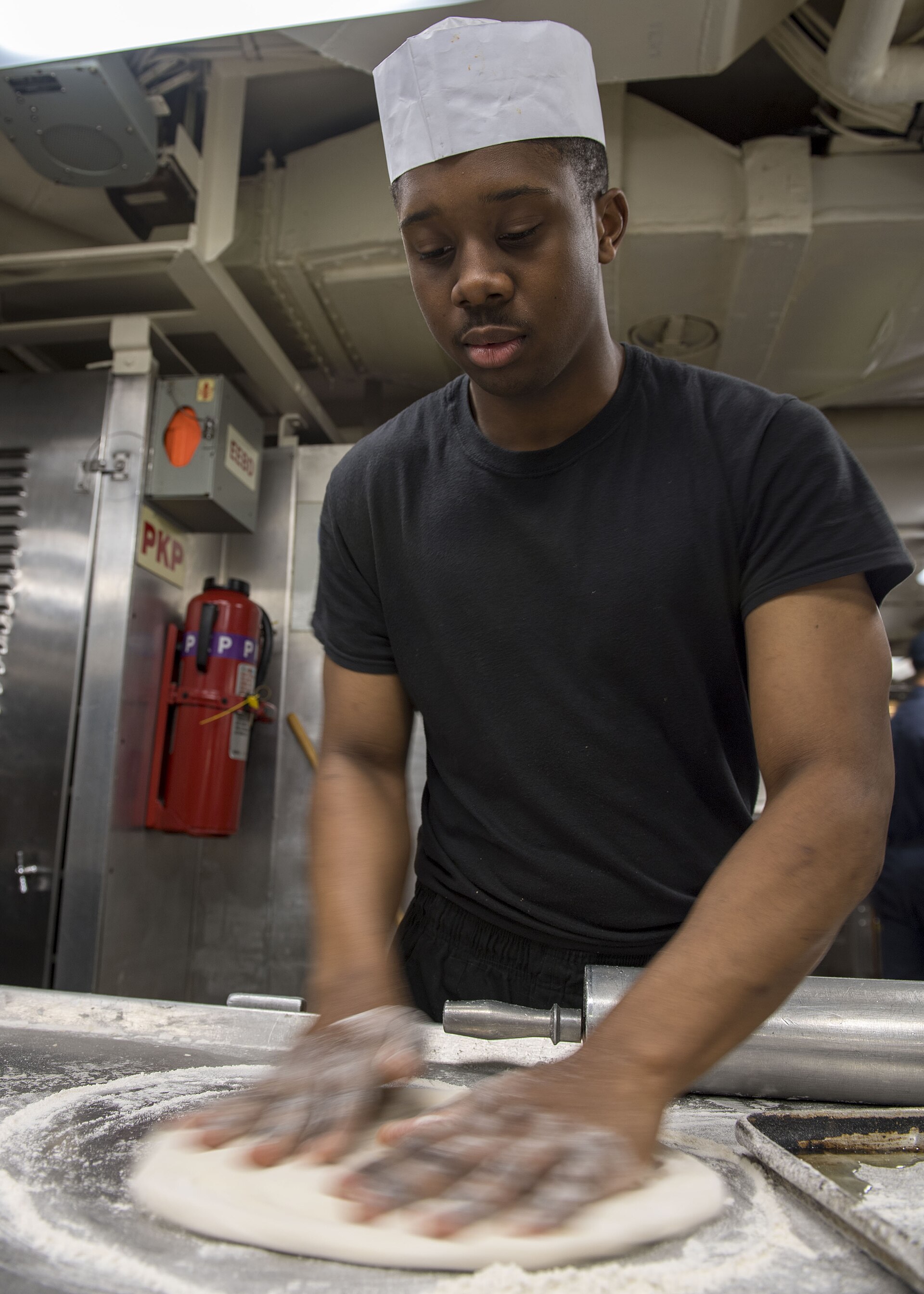 Hands stretching pizza dough on the bench.